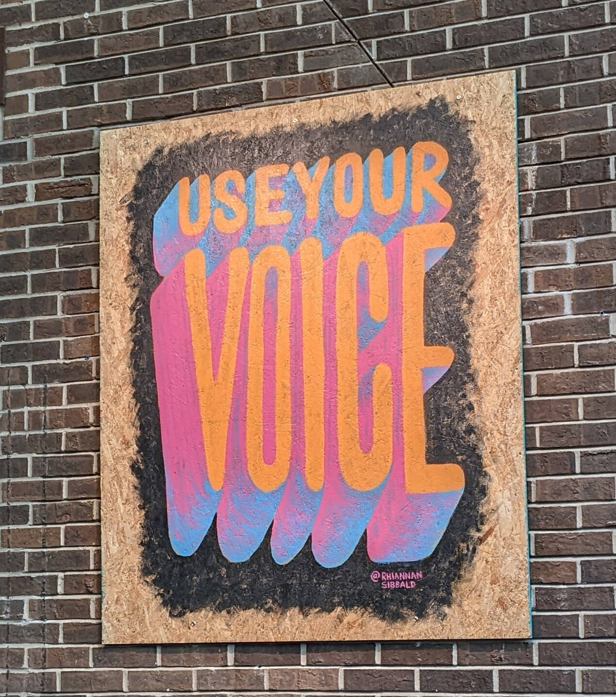 Painting on a large piece of word with the words "Use Your Voice."